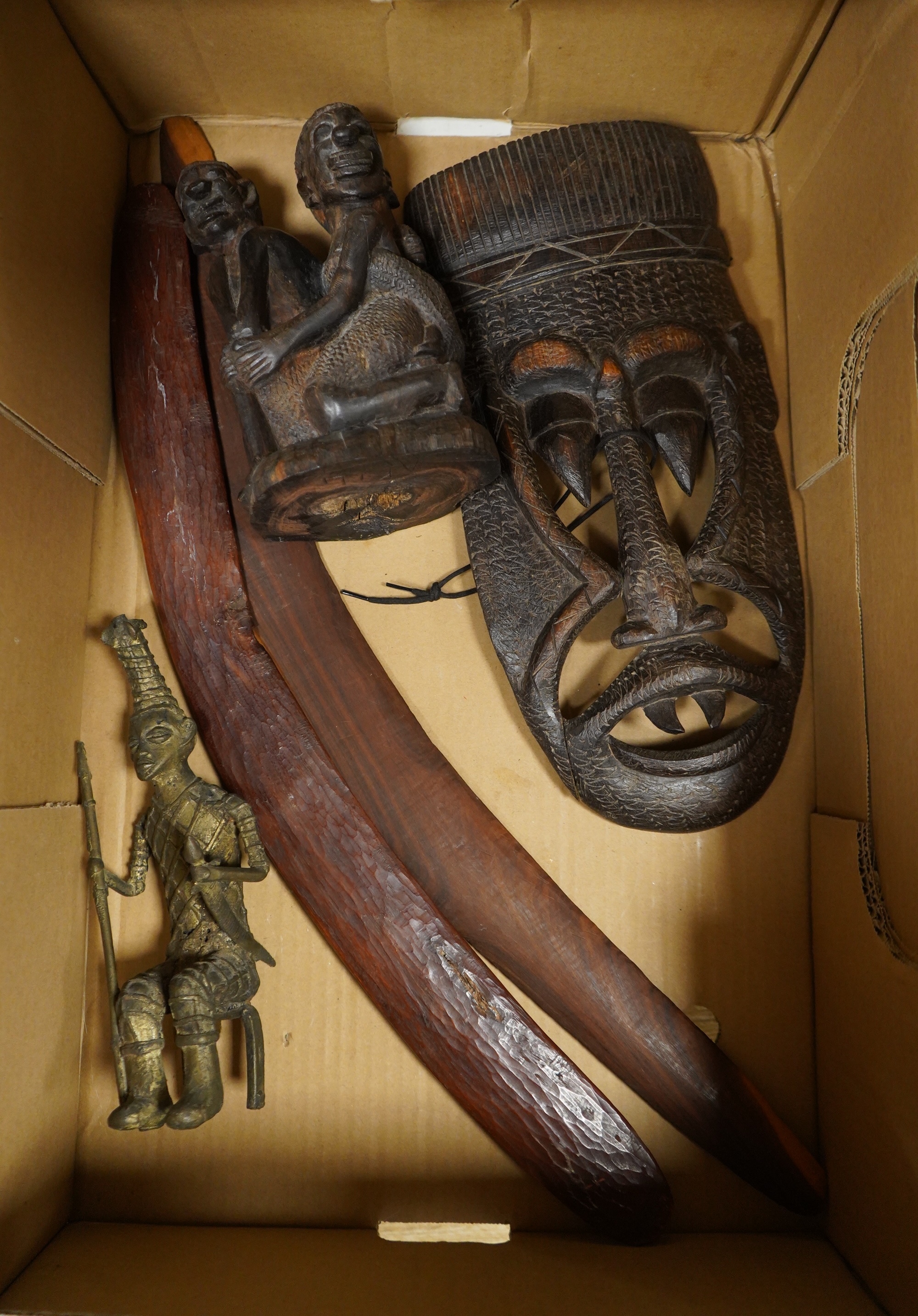Five ethnographic items; an early 20th century chip carved Australian boomerang-60cm long , together with a later example, a Benin bonds of a warrior seated on a stool, a Makonde African carved figure group and an Africa